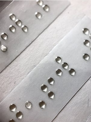 Adhesiu amb text Braille sobre vinil transparent